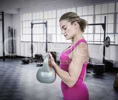Composite image of muscular woman exercising with kettlebell
