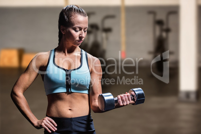 Composite image of fit woman exercising by lifting dumbbell