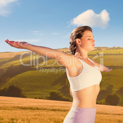 Composite image of sporty blonde standing on the beach with arms