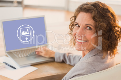 Composite image of businesswoman using laptop at desk in creativ