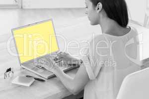 Composite image of businesswoman using laptop at desk in creativ