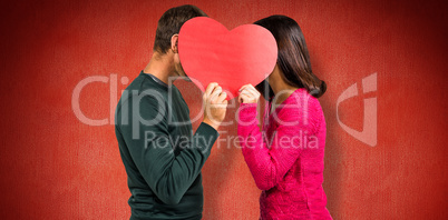 Composite image of couple covering faces with heart shape