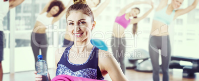 Composite image of fit brunette holding yoga mat