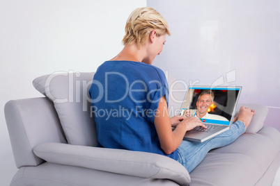 Composite image of blonde woman using her laptop on the couch