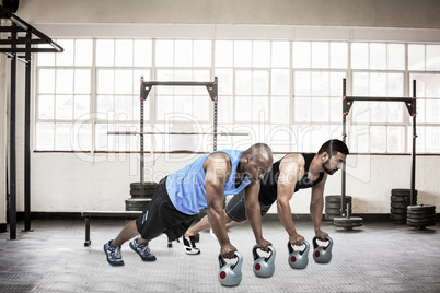 Composite image of strong friends using kettlebells together