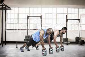 Composite image of strong friends using kettlebells together
