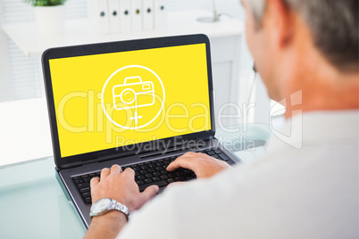 Composite image of man with grey hair typing on laptop