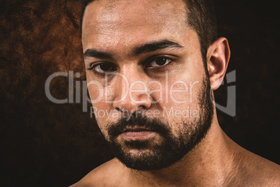 Composite image of muscular man frowning at camera