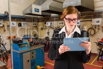 Composite image of redhead businesswoman using her tablet pc