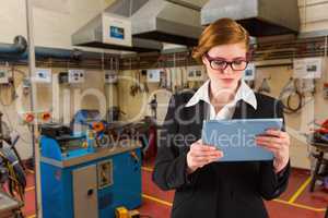 Composite image of redhead businesswoman using her tablet pc