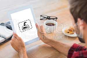 Composite image of rear view of man using tablet on wooden table