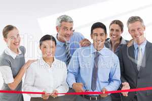 Composite image of business man cutting red strip