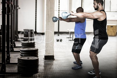 Composite image of strong friends lifting kettlebells together