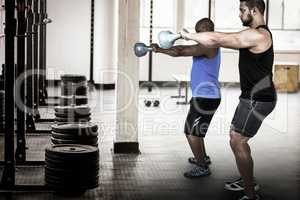 Composite image of strong friends lifting kettlebells together
