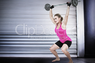 Composite image of sporty female bodybuilder lifting barebell