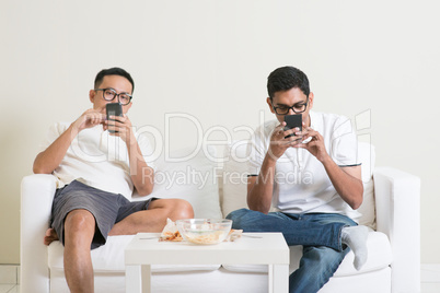 Bored friends playing own smartphones