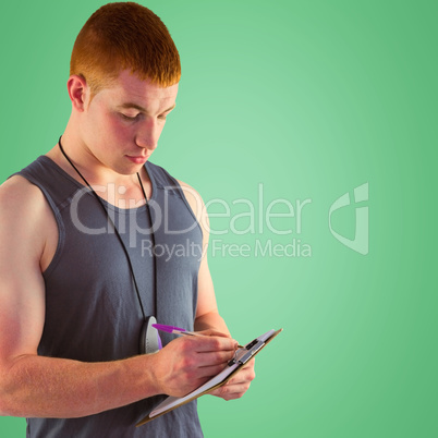 Composite image of fit personal trainer writing on clipboard