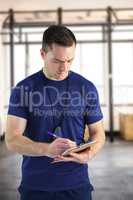 Composite image of attentive trainer writing on his clipboard