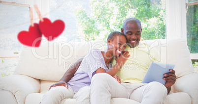Composite image of happy smiling couple using laptop on couch Composite image of happy smiling couple using laptop on couch