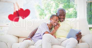Composite image of happy smiling couple using laptop on couch