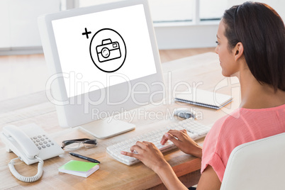 Composite image of businesswoman using computer at desk in creat