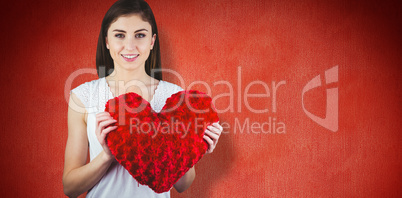 Composite image of woman holding heart shape cushion