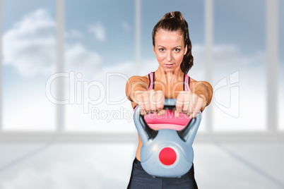 Composite image of portrait of fit woman lifting kettlebell