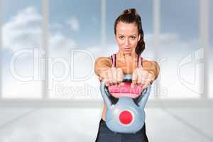 Composite image of portrait of fit woman lifting kettlebell