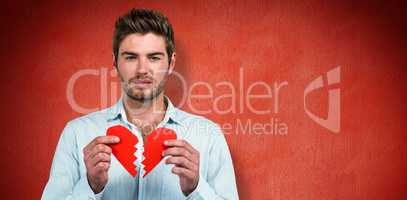 Composite image of sad man holding heart halves