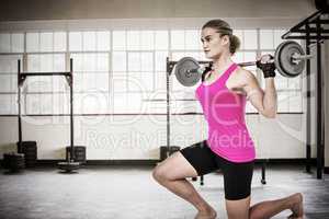 Composite image of sporty female bodybuilder lifting barebell