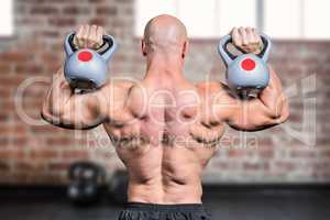 Composite image of rear view of bald man lifting kettlebells