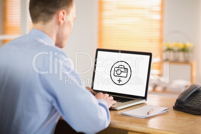 Composite image of businessman working on his laptop