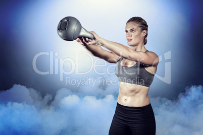Composite image of muscular woman swinging heavy kettlebell