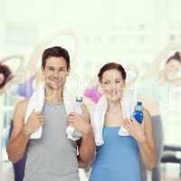 Composite image of portrait of a happy fit couple with water bot