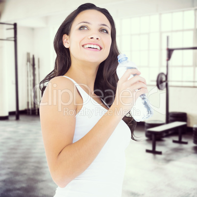 Composite image of pretty brunette drinking bottle of water