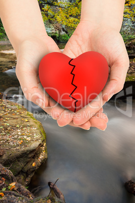 Composite image of couple holding broken heart in hands