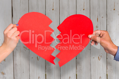 Composite image of two hands holding broken heart