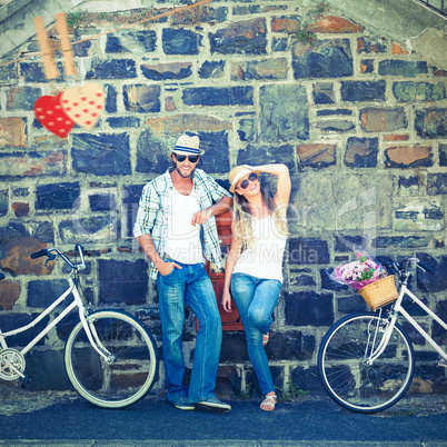 Composite image of attractive couple standing with bikes