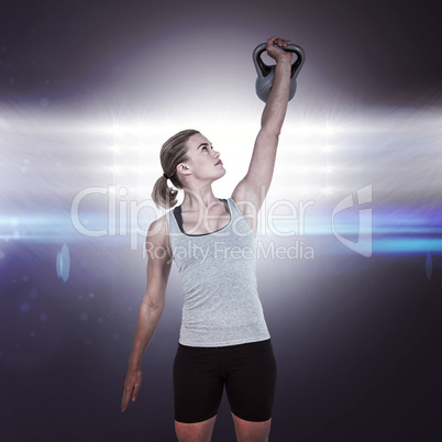 Composite image of serious muscular woman lifting kettlebell