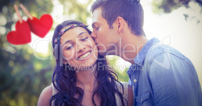 Composite image of cute couple kissing in the park