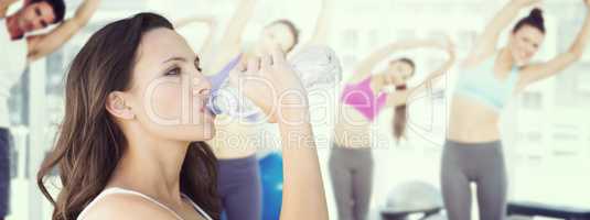 Composite image of beautiful woman drinking water from bottle