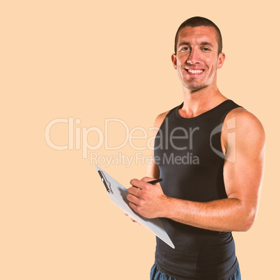 Composite image of smiling sports coach writing on clipboard