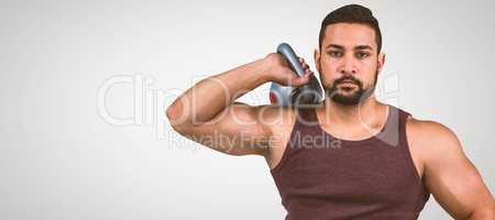 Composite image of muscular serious man holding a kettlebell