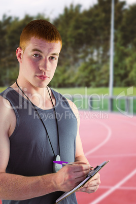 Composite image of fit personal trainer writing on clipboard