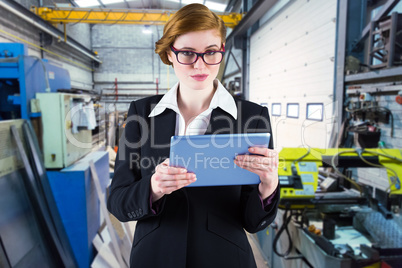 Composite image of redhead businesswoman using her tablet pc