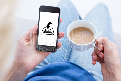 Composite image of woman using her mobile phone and holding cup