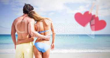 Composite image of happy couple embracing and looking at the sea