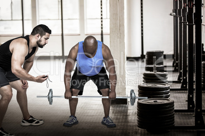 Composite image of man lifting barbell with trainer