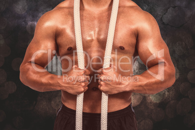 Composite image of muscular man with battle rope