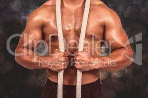 Composite image of muscular man with battle rope